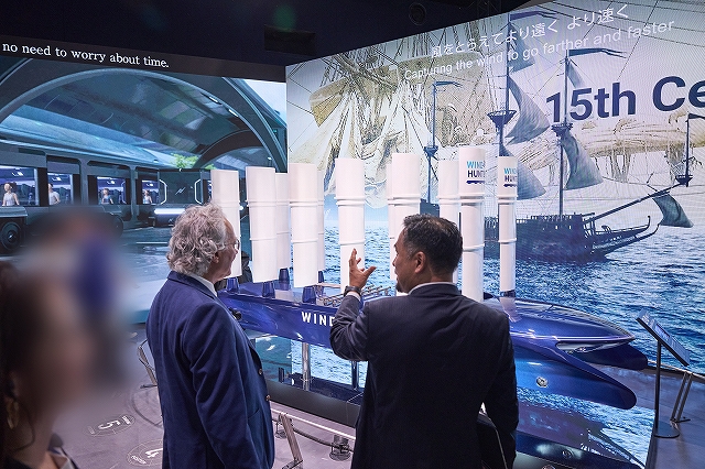 「ウインドハンター」の模型と、模型を前に説明を聞く参加者の写真です