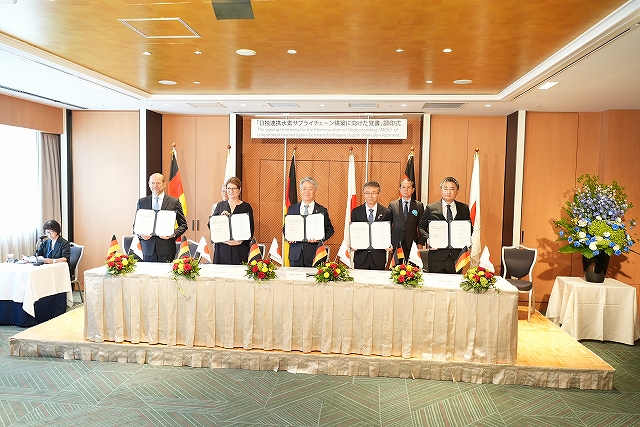 関係者がMOUの締結文書を掲げている写真です